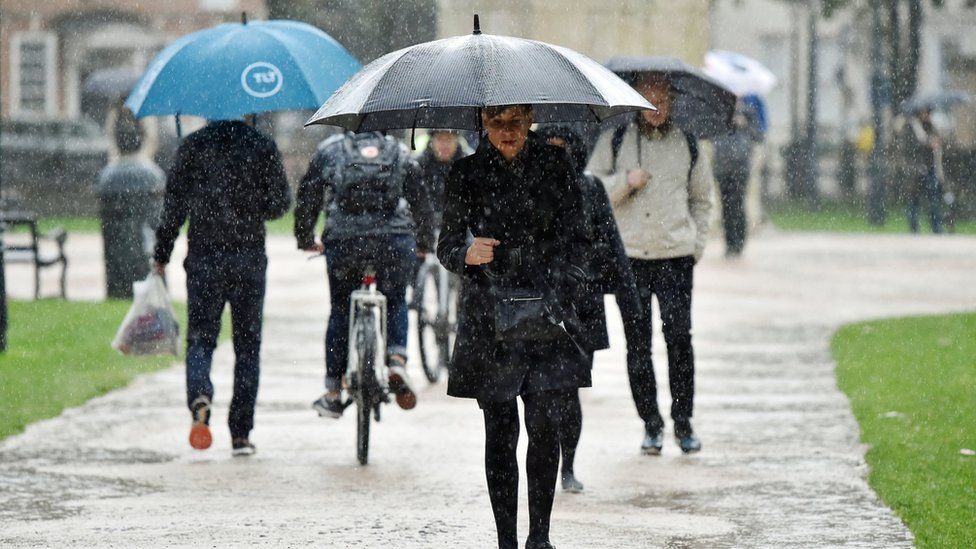 people walk with umbrellas in Bristol