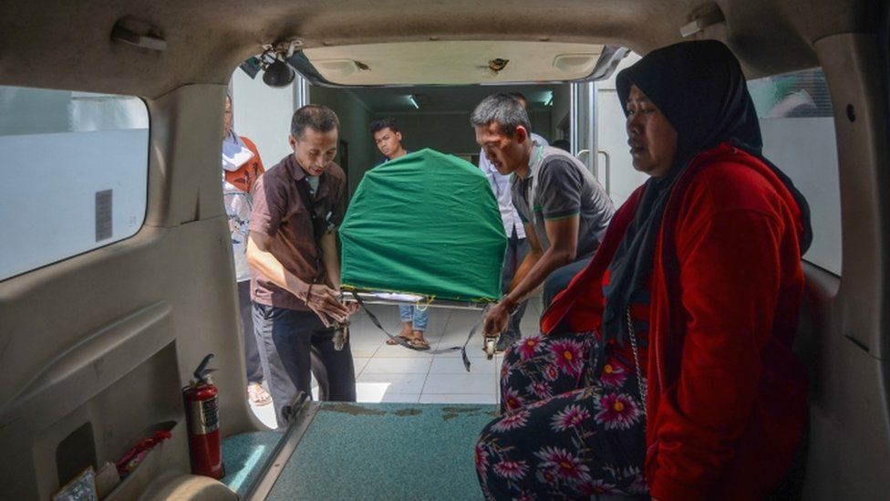 Body of a man who died from tainted alcohol is carried into an ambulance in Cicalengka