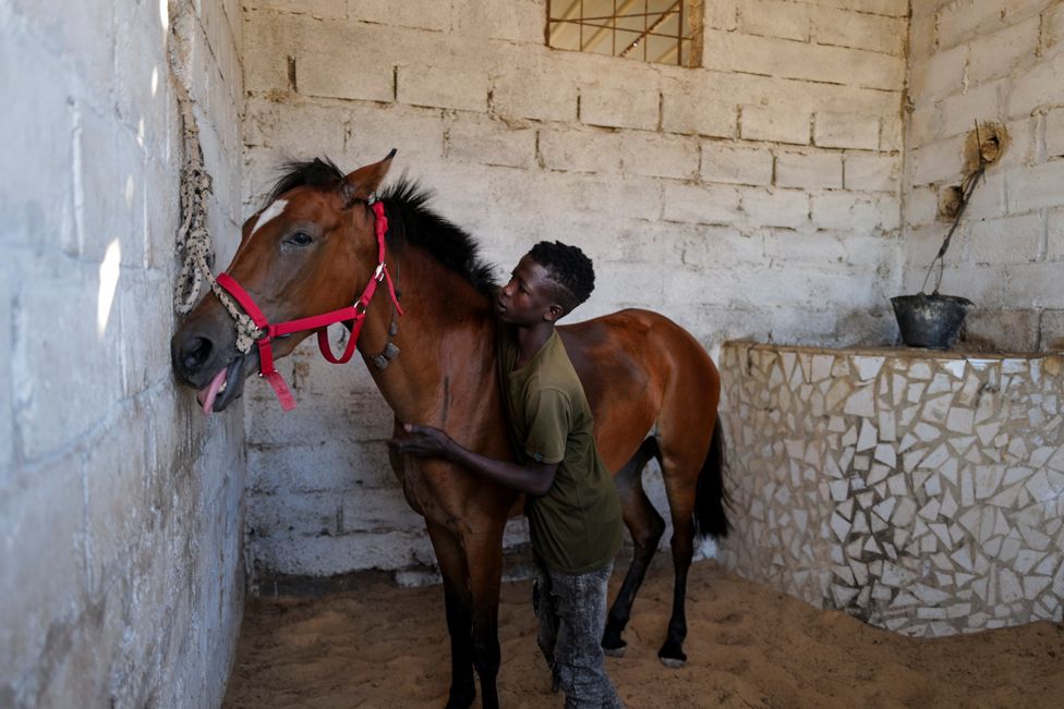 Fallou Diop hugs his horse at the Lambafar stable in Niaga, Senegal, 27 January 2021