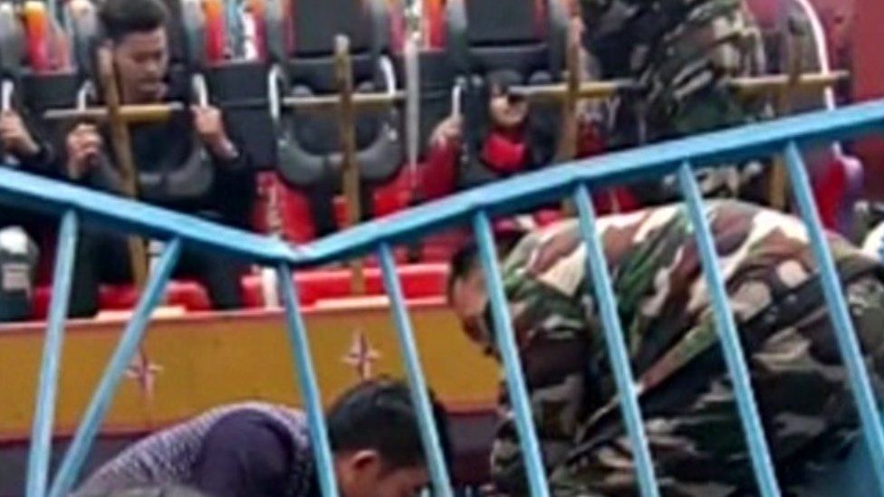 People at a theme park in China look on as a girl is attended to after being flung from a ride