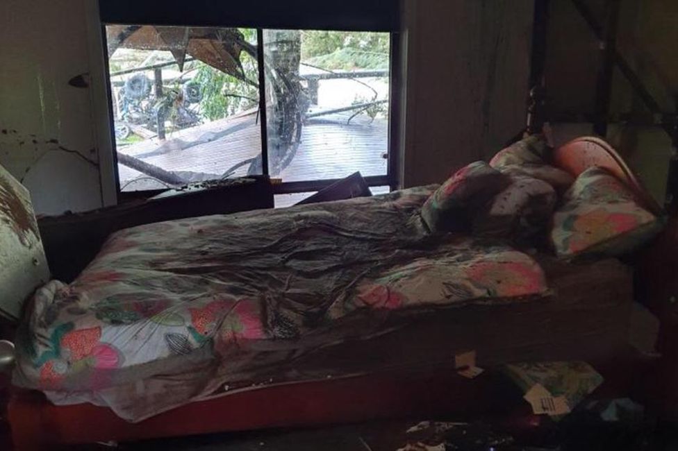 Furniture and debris strewn around the waterlogged living room in the Costigan family home
