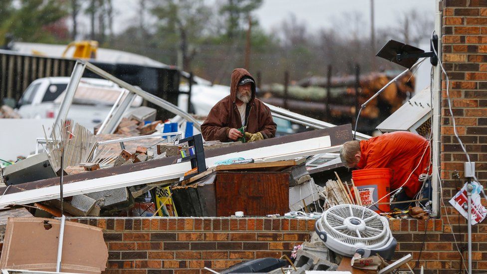 A man and his son help a family clean up their business after a tornado in Rosalie, Alabama, on 30 November 2016