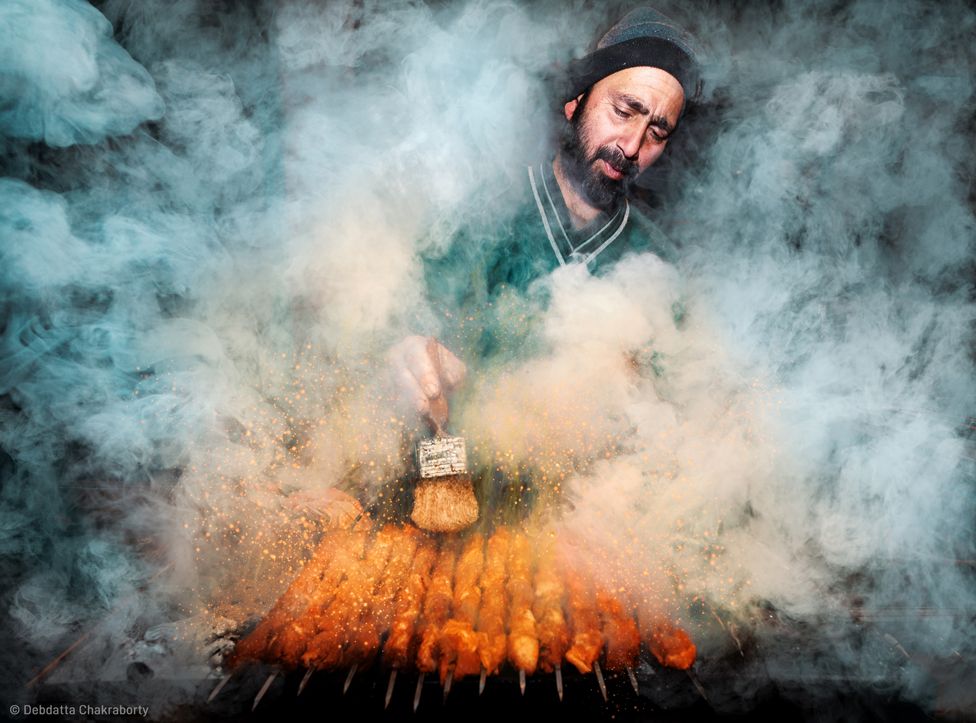 Уличный торговец едой в дыму готовит еду