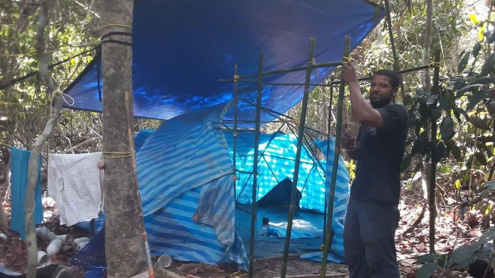 Man putting up tent made of waste plastic.