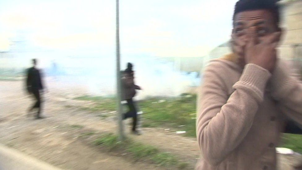Mohammed, 16, from Eritrea covers his mouth as police fire tear-gas canisters in the Jungle camp at Calais