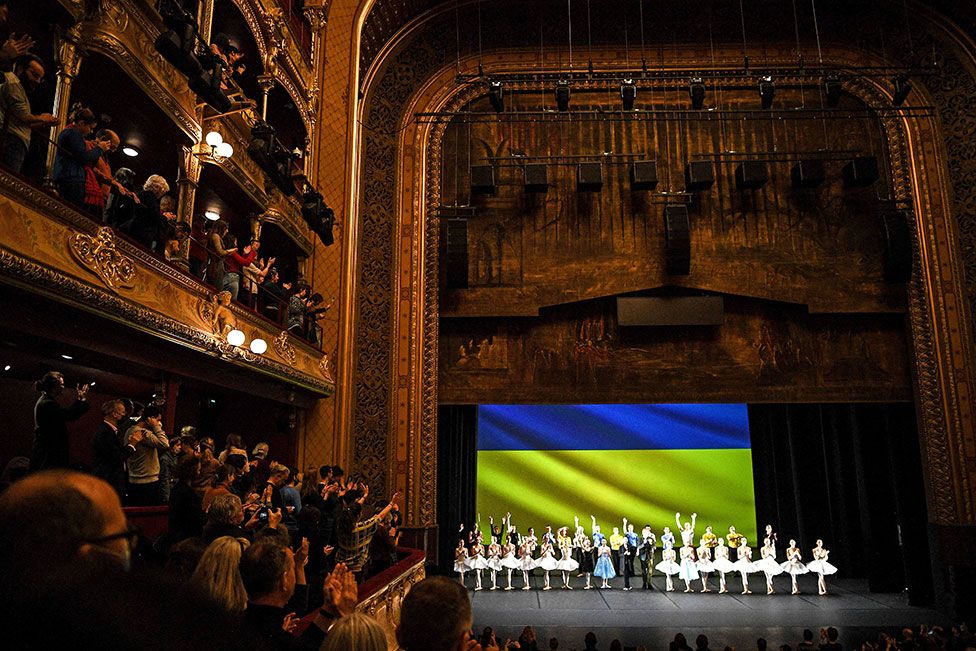 Ukrainian dancers of the Kyiv City Ballet acknowledge the audience at the end of their performance with a flag of Ukraine displayed on stage at the Theatre du Chatelet in Paris, France, on 8 March 2022