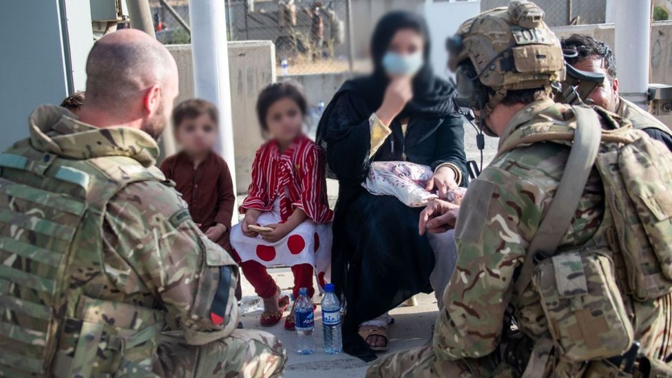 Image of British soldiers talking to a woman and her two children