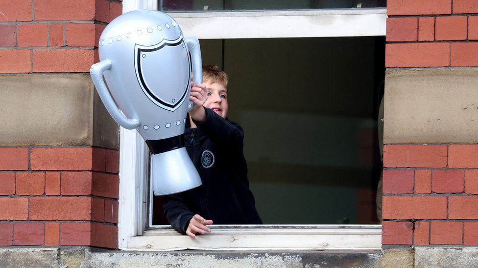 A young Manchester City fan holds an inflatable Premier League trophy during the victory parade