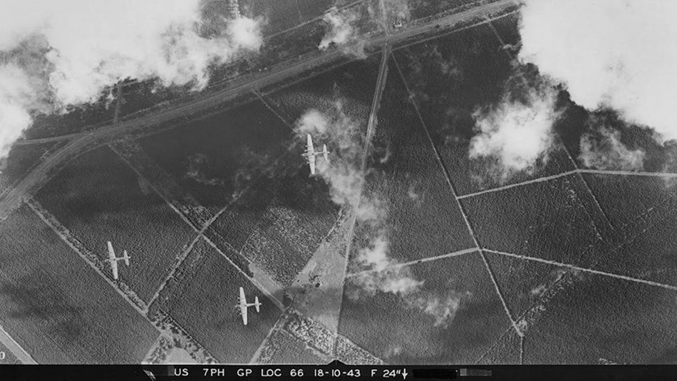 A vertical aerial photograph looking down through a break in the clouds on Eighth Air Force B-17 bombers flying over The Brecks area of Norfolk.