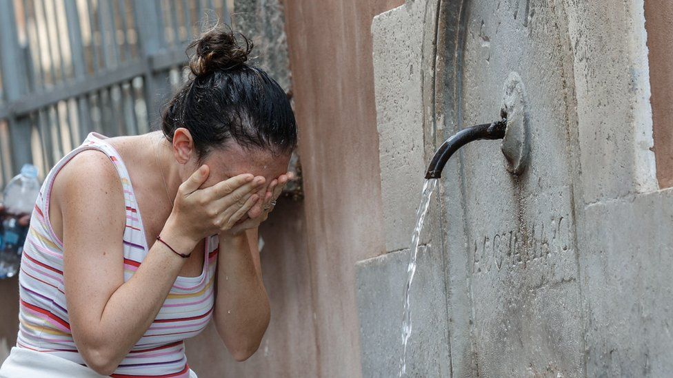 A woman cools off at a fountain in Italy