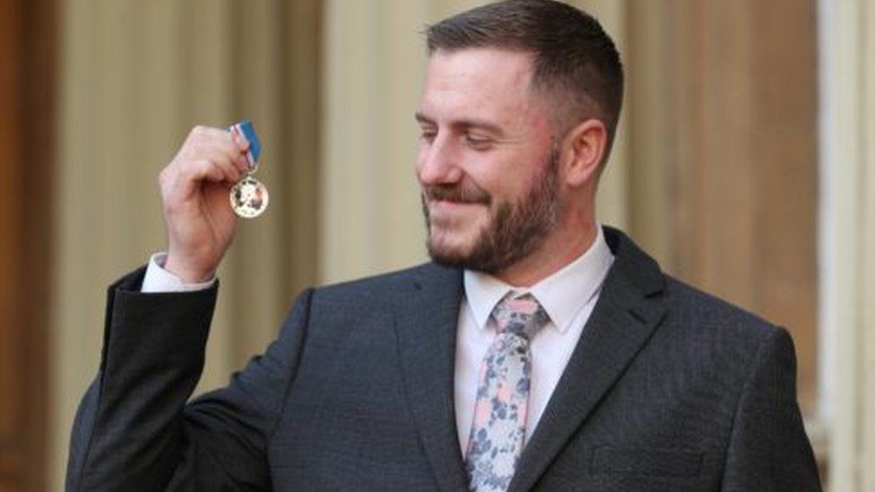 Image of Luke Ridley holding his medal and smiling