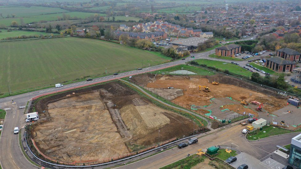An aerial shot shows the whole site being dug up