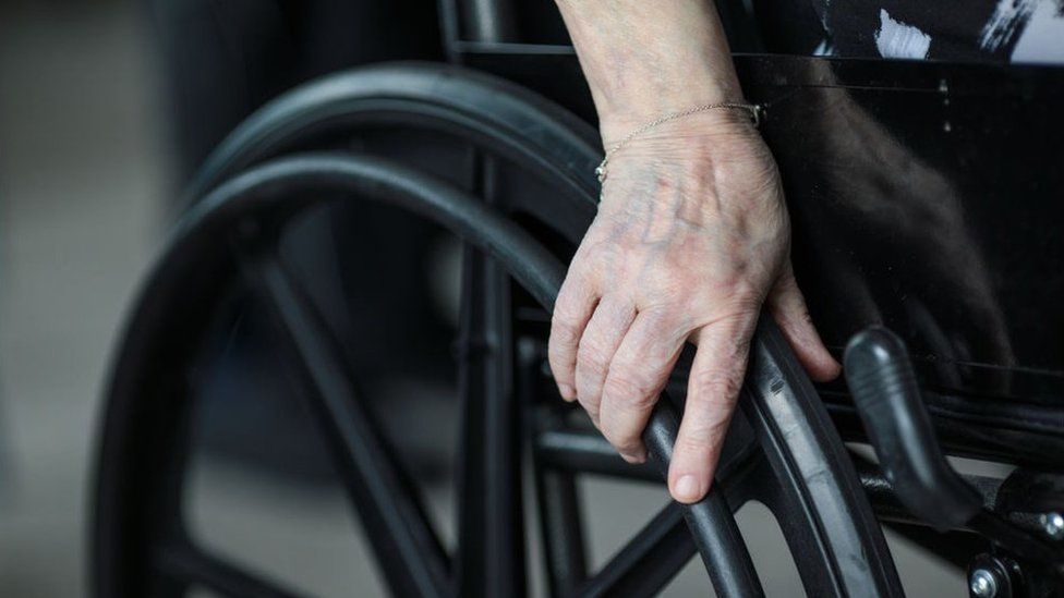 unidentified person holding wheelchair wheel