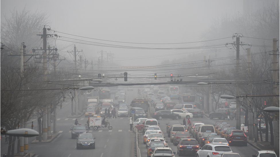 Cars drive below a blanket of smog on a heavily polluted day in Beijing on December 26, 2015