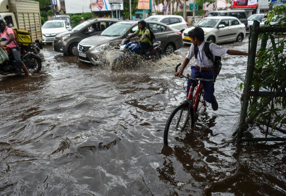 School students are seen making their way through a flooded road in Kolkata , India , on 2 August 2023.