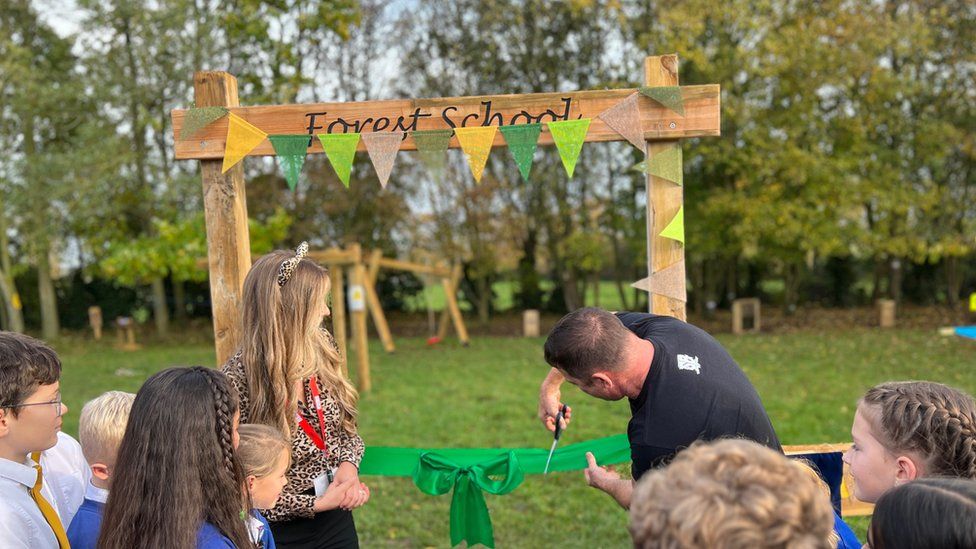 Mrs Charley Oldham (left) and Steve Backshall cutting a ribbon to open the forest school