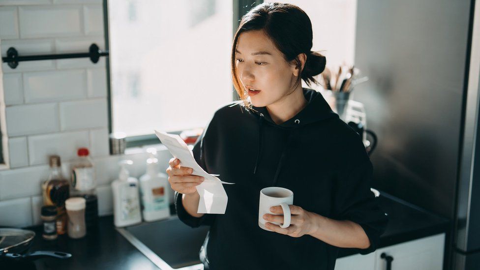 Woman looking astatine  vigor  measure  portion    having a cupful  of tea