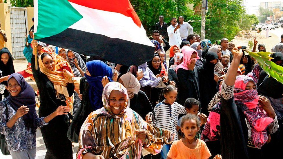 Sudanese demonstraters wave their national flag as they celebrate in Khartoum
