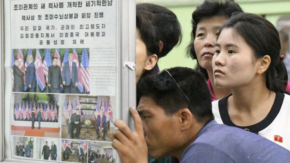 North Koreans watch the displayed local newspapers