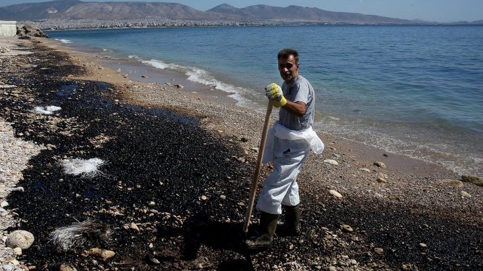A clean-up worker struggles to remove an oil spill from a beach on the coast around Athens, Greece, on 13 September 2017.