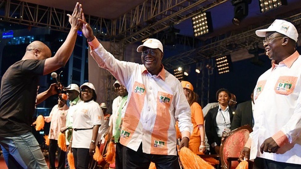 Alassan Ouattara (C) dances with the singer Asafo (L) of the group Magic System at the end of a campaign parade on 23 October 2015 in Abidjan