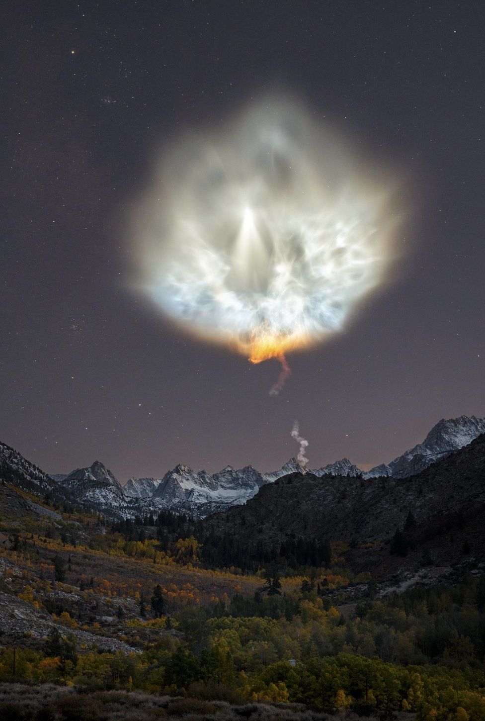 Landscape view of the smoke plume of a rocket, above mountains