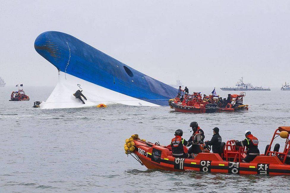 This photo taken at sea some 20 kilometres off the island of Byungpoong in Jindo on 16 April 2014 shows coast guard members searching for passengers near a South Korean ferry (C) that capsized on its way to Jeju island from Incheon