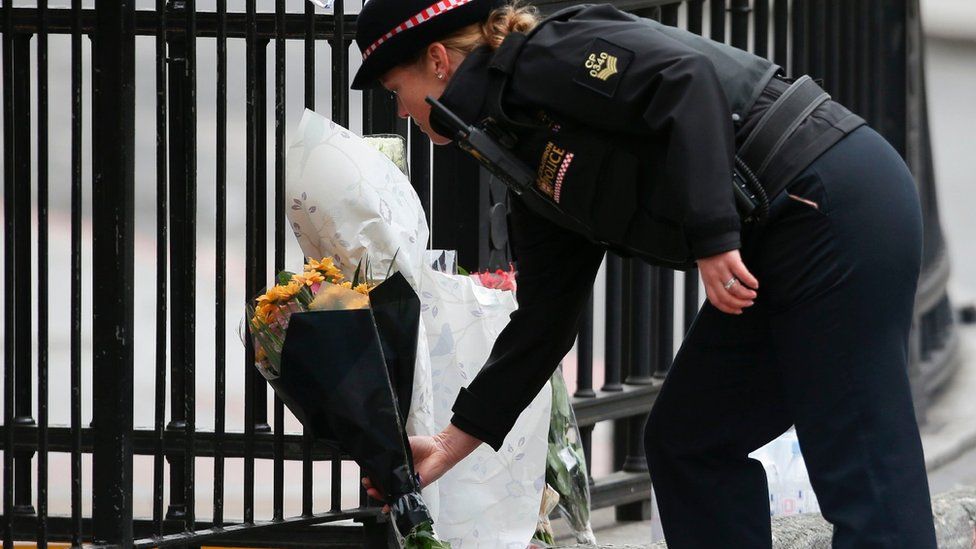 A police officer prepares to lay flowers near London bridge