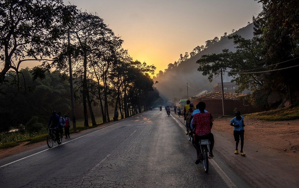 Residents cycle along a road at dawn on the outskirts of Kigali, Rwanda.