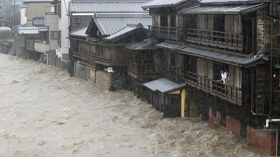 A man on a balcony watching the Isuzu river flood his street in Ise, central Japan