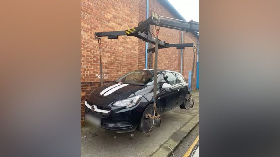 Car being picked up by crane