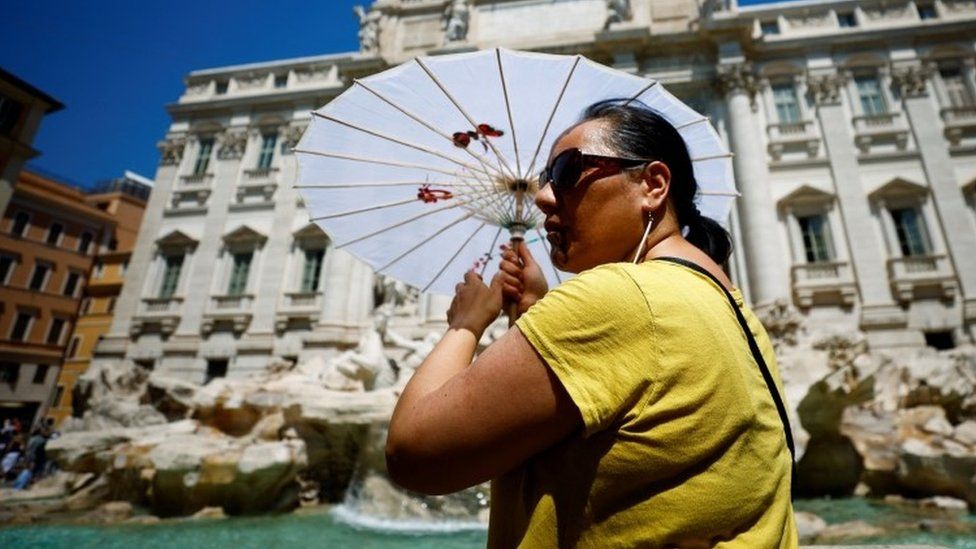 Женщина держит зонтик у фонтана Треви в Риме