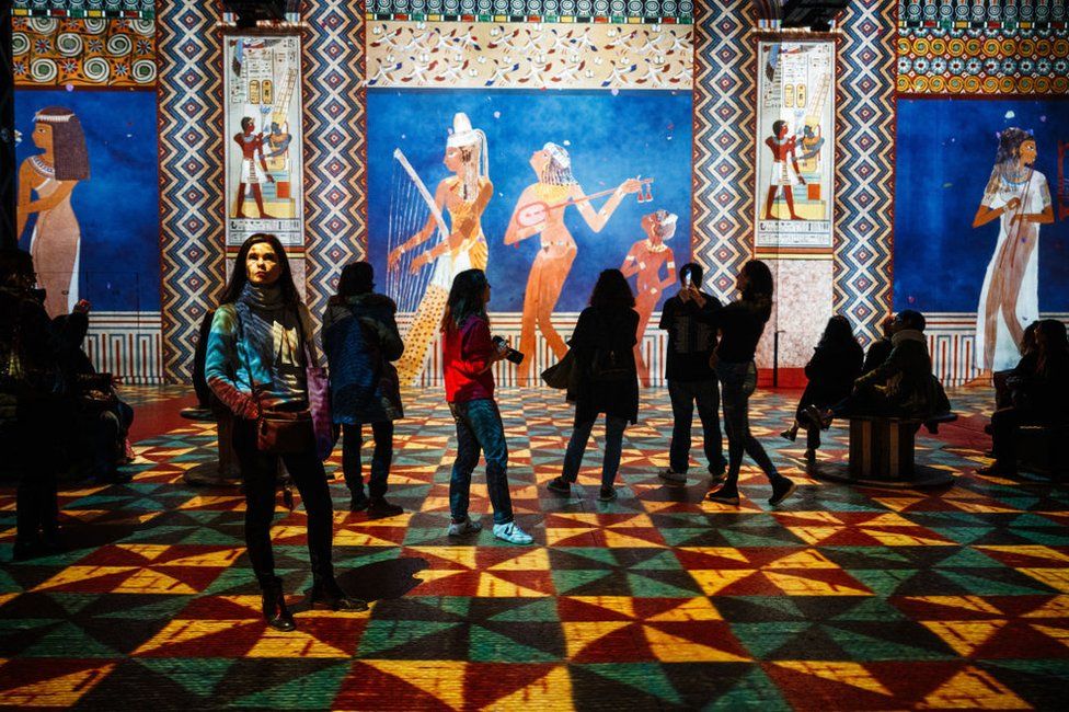 Visitors look at light installations at the Atelier des Lumieres, during a press preview of the exhibition titled "Egyptian Pharaons, from Cheops to Ramses II".