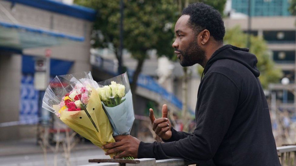 A man leaving flowers at the site of the stabbing