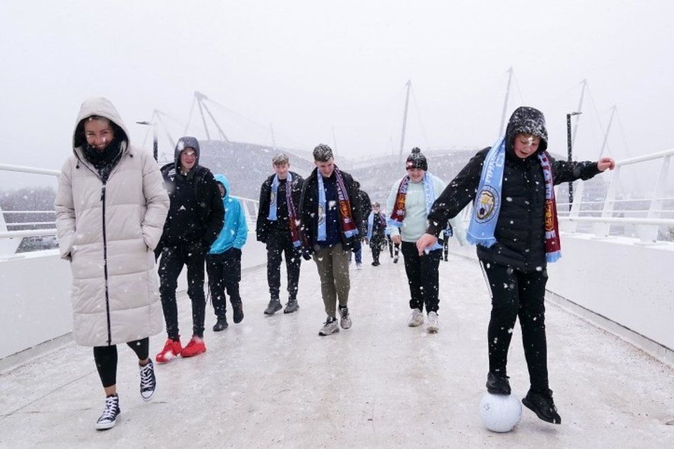 Fans cross the bridge to the stadium in the snow before the Premier League match at the Etihad Stadium, Manchester.