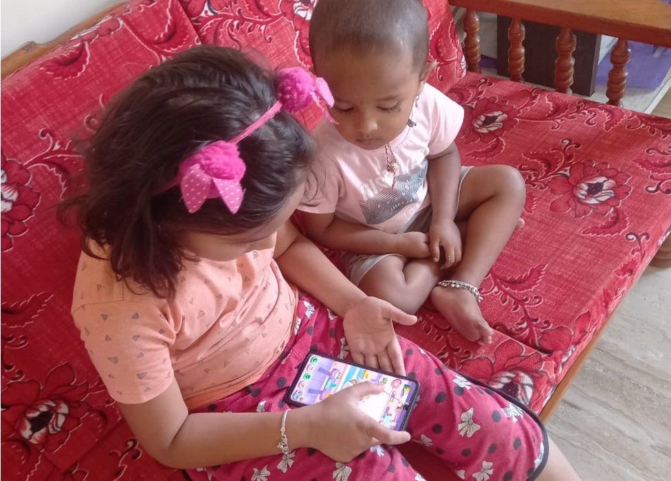 Two young children looking at a game on the phone