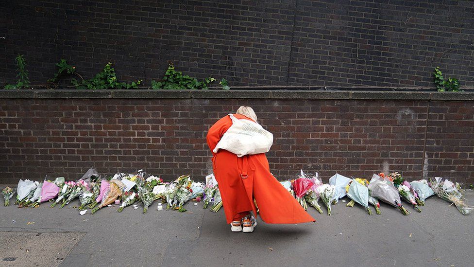 A woman lays flowers near the scene of a stabbing in Croydon