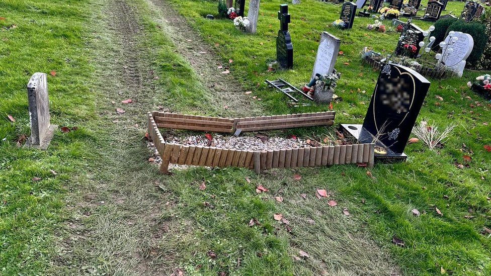 A grave with digger tracks going over it