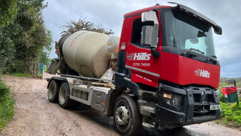 A red truck driving out of the estate