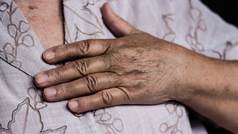 A woman with her hand on her chest
