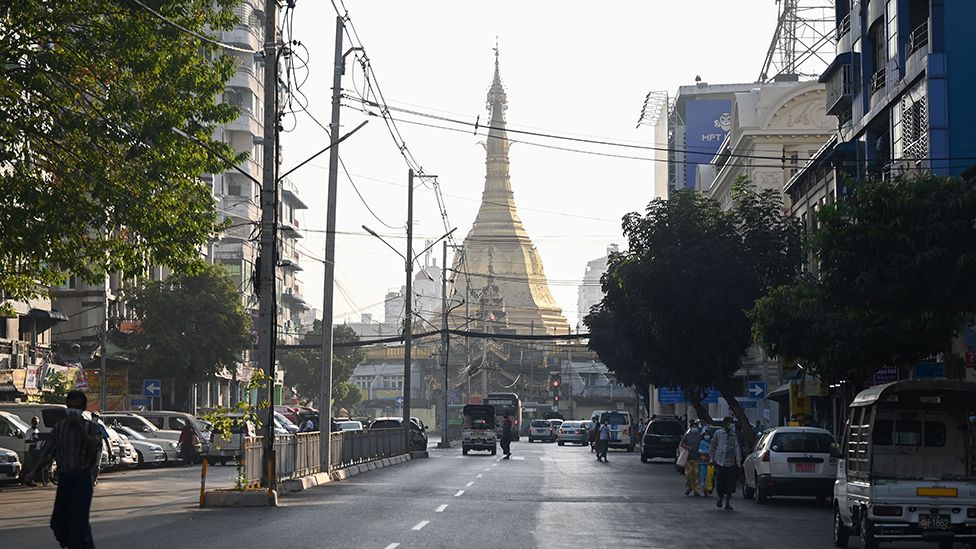 People walk next to the Sule Pagoda on an empty road in central Yangon on February 1, 2021