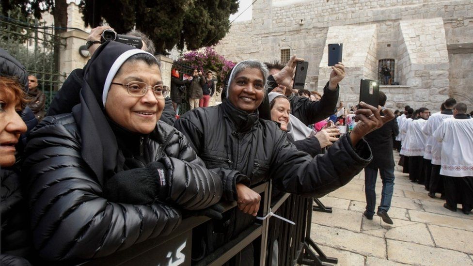 Nuns watch a procession at the Church of the Nativity in Bethlehem on December 24, 2017.
