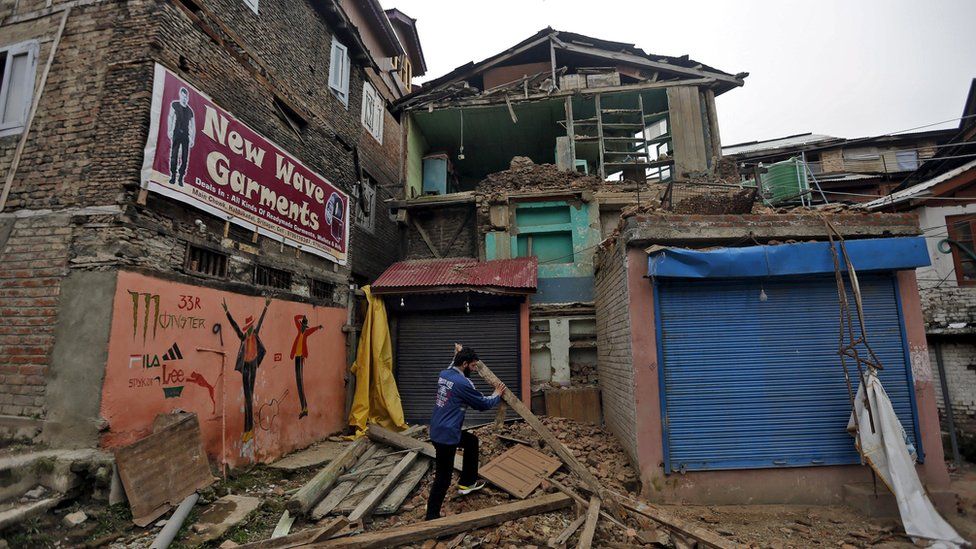 A man clears debris after his house partially collapsed following an earthquake, in Srinagar, India April 10, 2016