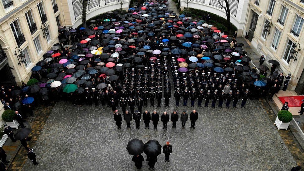 Officials of the French gendarmerie nationale and French Interior Minister Gerard Collomb hold a minute of silence
