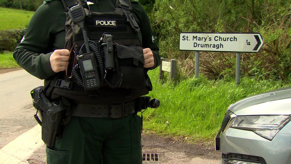 A police officer stands near a sign pointing to St Mary's Church