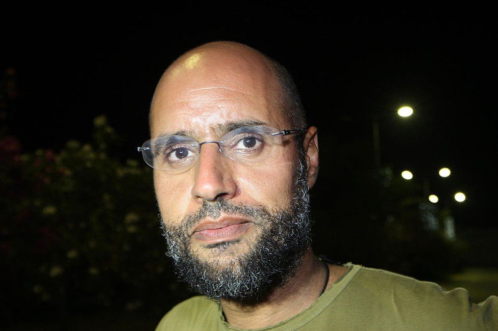 Saif al-Islam Gaddafi appears in front of supporters and journalists at his father's residential complex in Tripoli in 2011.