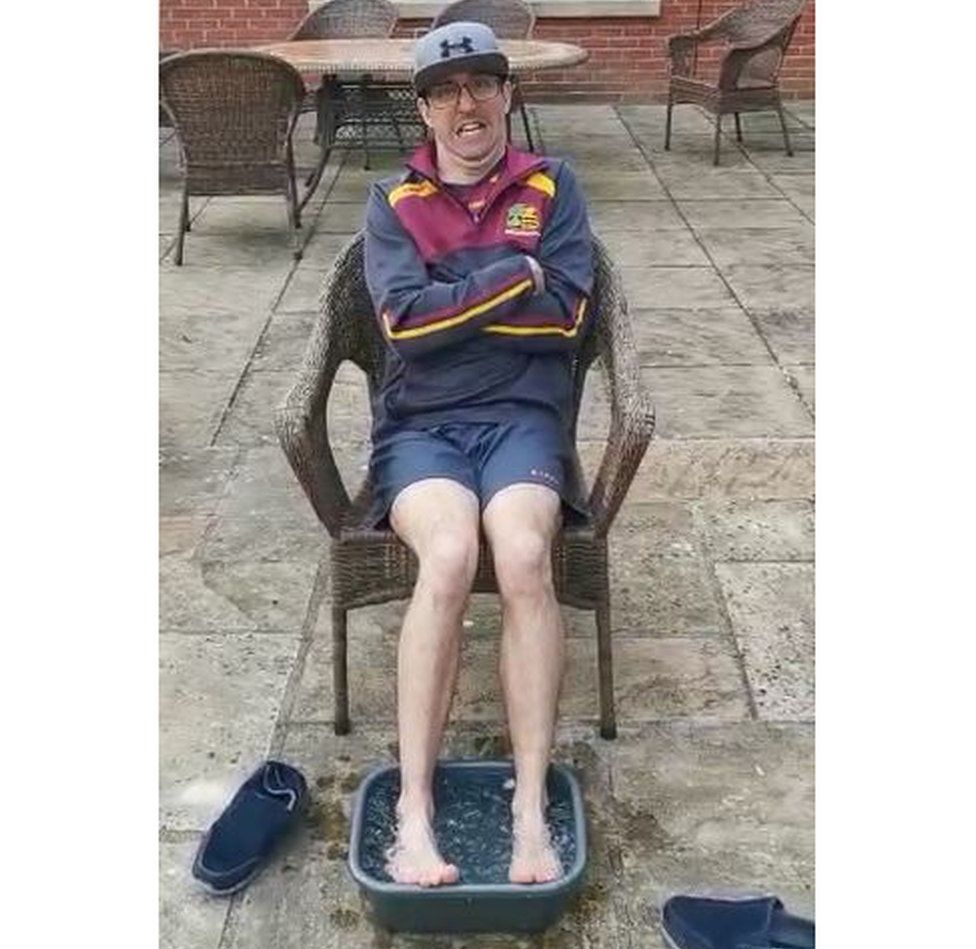 Tom sitting on a chair with his feet in a bowl of ice, looking very cold!
