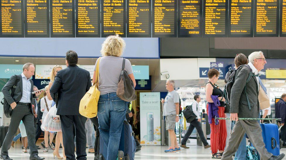 Commuters in a train station looking at the arrivals board