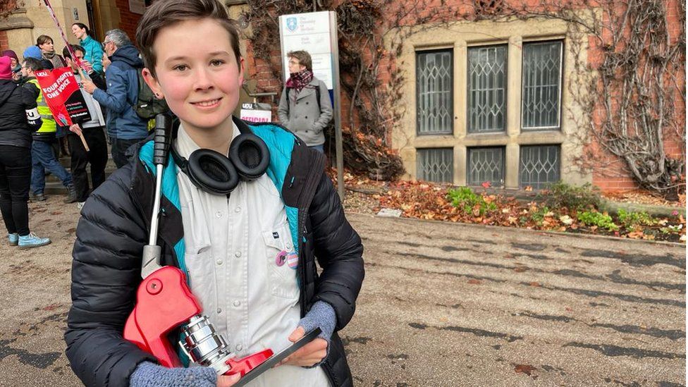 Студент Шеффилдского университета держит в руках станок для изготовления значков