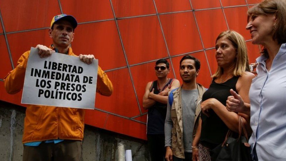 Venezuelan opposition leader and Governor of Miranda state Henrique Capriles (L) poses for a photo with a placard that reads "Immediate release of political prisoners" in Caracas, Venezuela July 3, 2017.